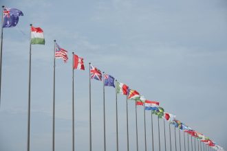 Fileira de bandeiras internacionais hasteadas, simbolizando relações diplomáticas e alianças entre países