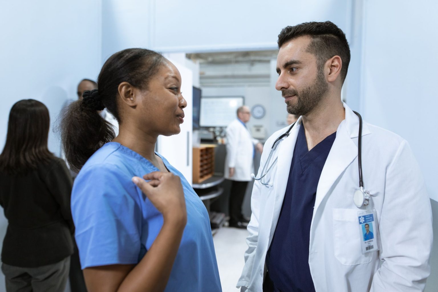 Profissionais de saúde conversam em um corredor de hospital sobre o atendimento aos pacientes.